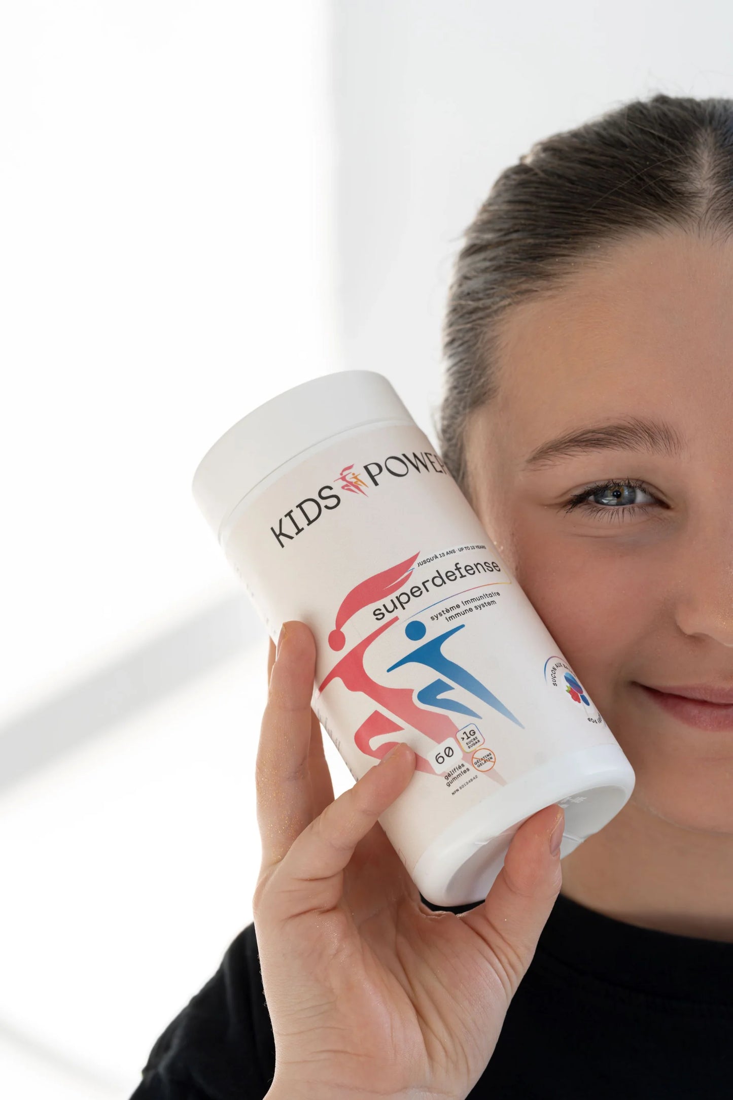 Fille tenant Kids Power Superdefense gummies système immunitaire enfant